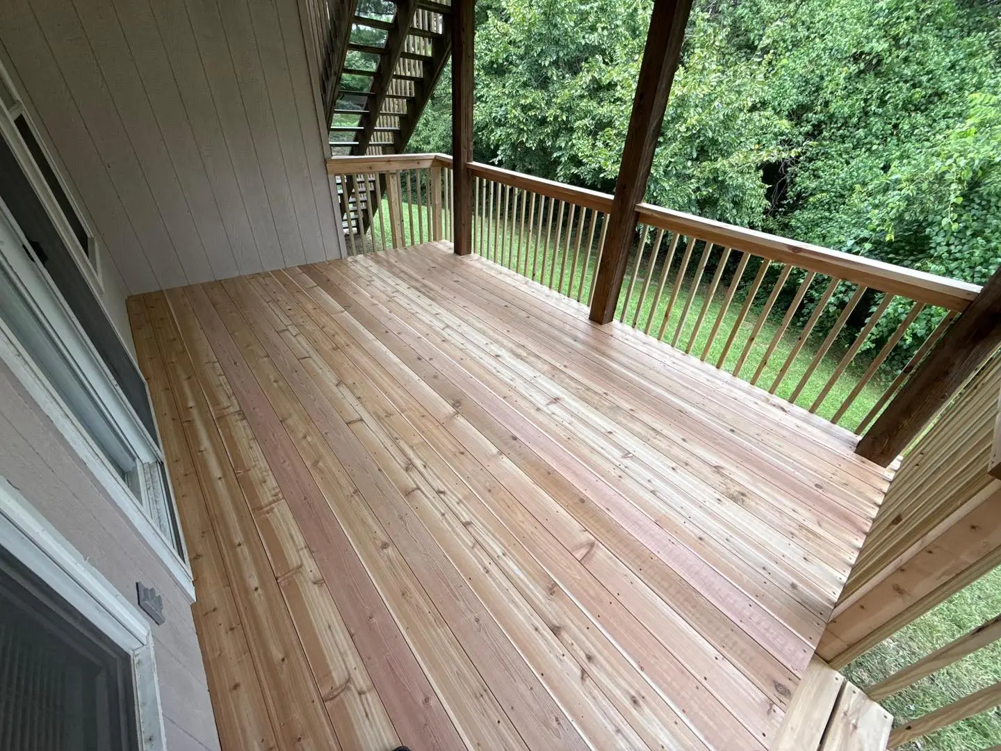 newly constructed wooden deck attached to a residential home overlooking a lush backyard in kansas city