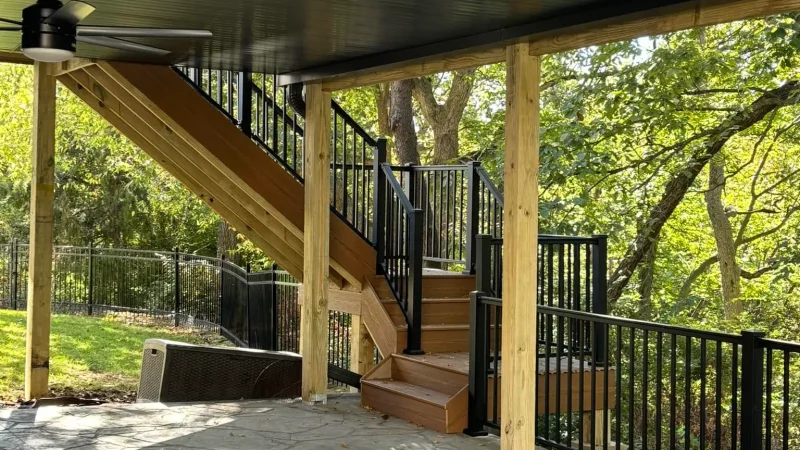under-deck patio area with stone flooring and wooden staircase in a kansas city backyard