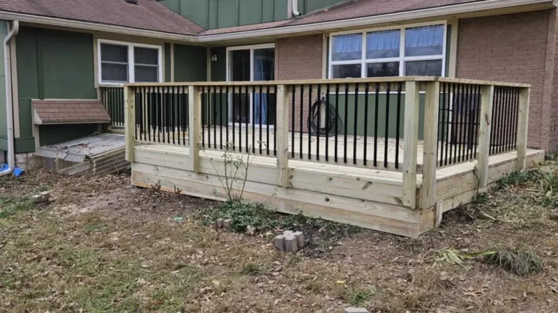 newly constructed wooden deck with metal railings attached to a green house in kansas city