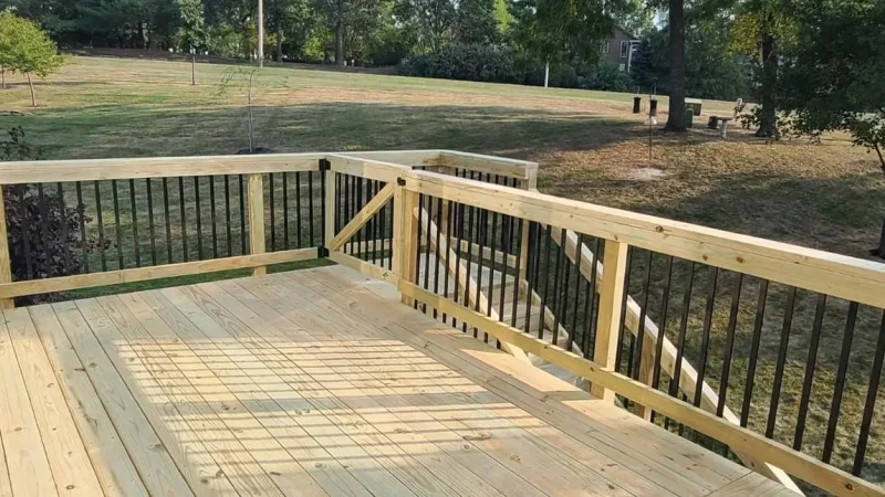 newly constructed wooden deck with black metal balusters overlooking a grassy backyard in kansas city