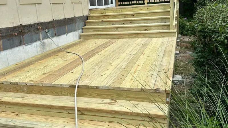 newly built wooden deck with steps leading to a patio in a suburban kansas city home